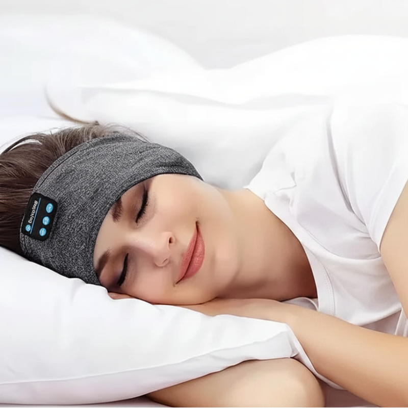 Person wearing a gray Bluetooth sleep headband while lying down.