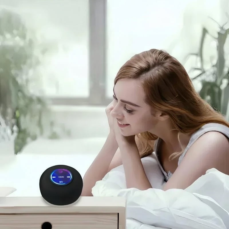 Nova Haus black spherical Bluetooth speaker with LED lights on a nightstand next to a woman in bed.